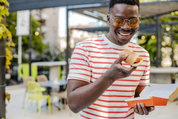 Smiling customer eating a hot dog